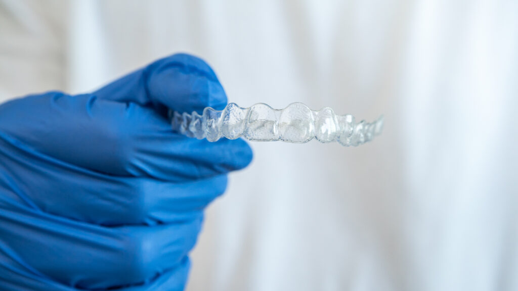 DentiQue Stomatologia Wrocław hand in gloves holding dental aligner retainer in 2024 12 07 13 00 21 utc